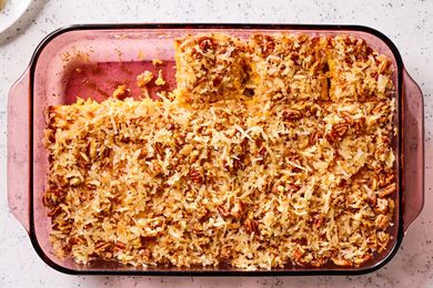 Overhead view of a glass baking dish of pineapple coconut cake with two slices removed