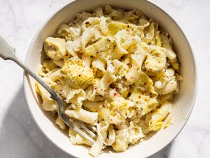 Bowl of pasta with artichoke hearts and lemon shavings fork placed on the side