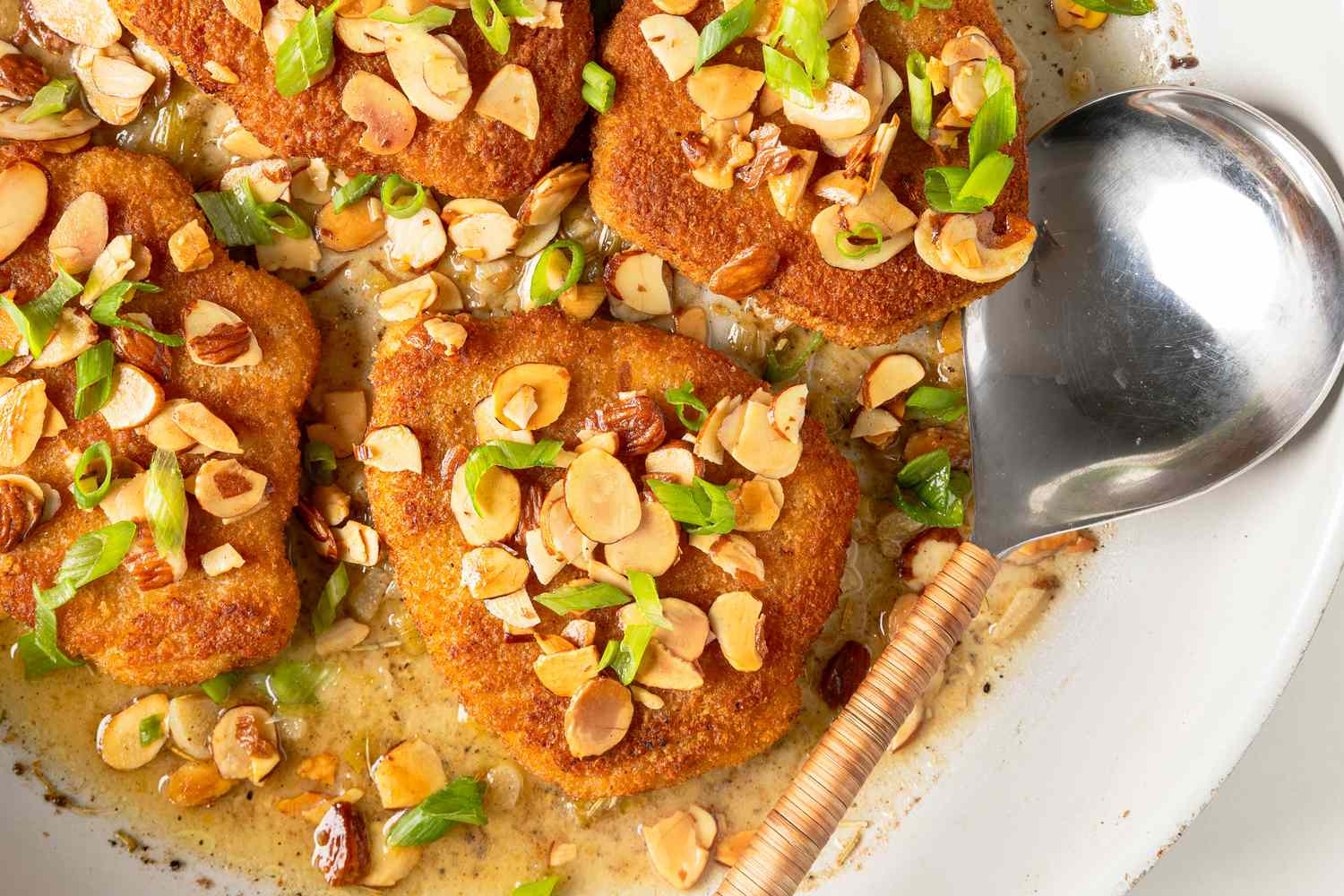 close up of Easy Chicken Almondine in a skillet with a large serving spoon
