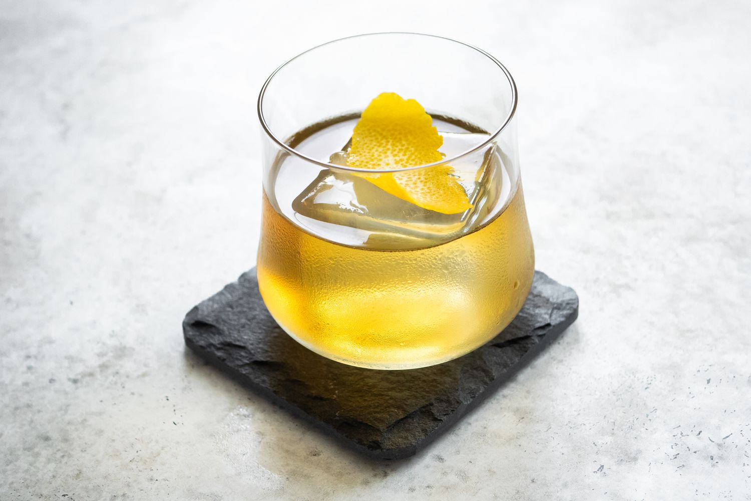 Rusty Nail on a Granite Coaster Garnished with Lemon Peel