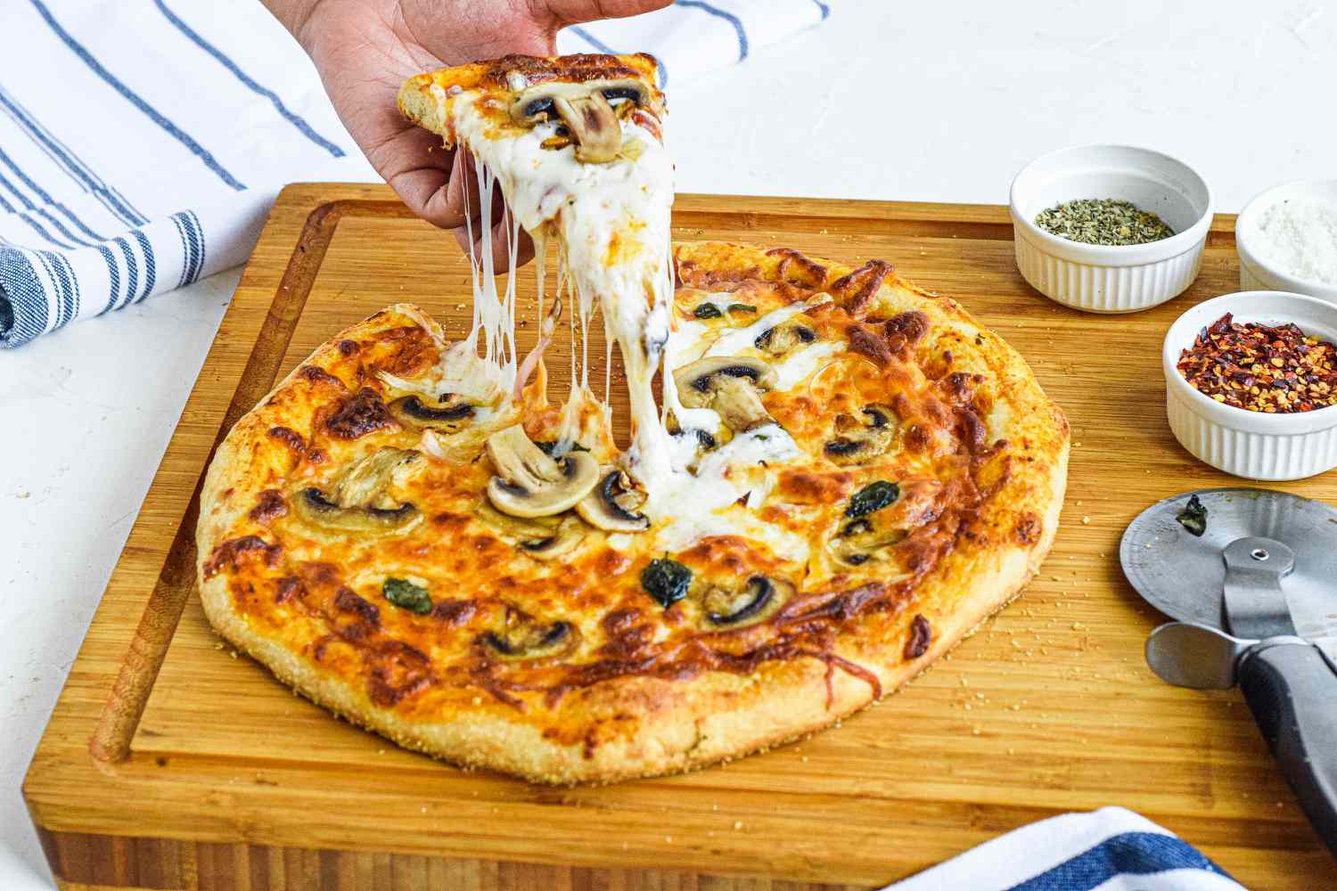Side view of a cheesy homemade pizza recipe on a wooden cutting board.