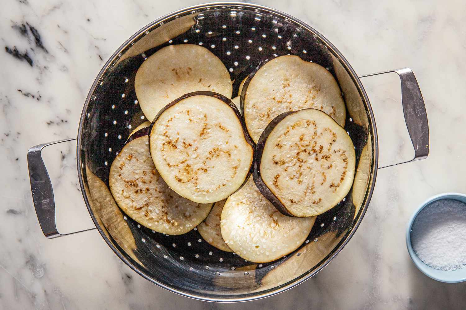 Colander with sliced eggplant to make a simple eggplant parmesan recipe.