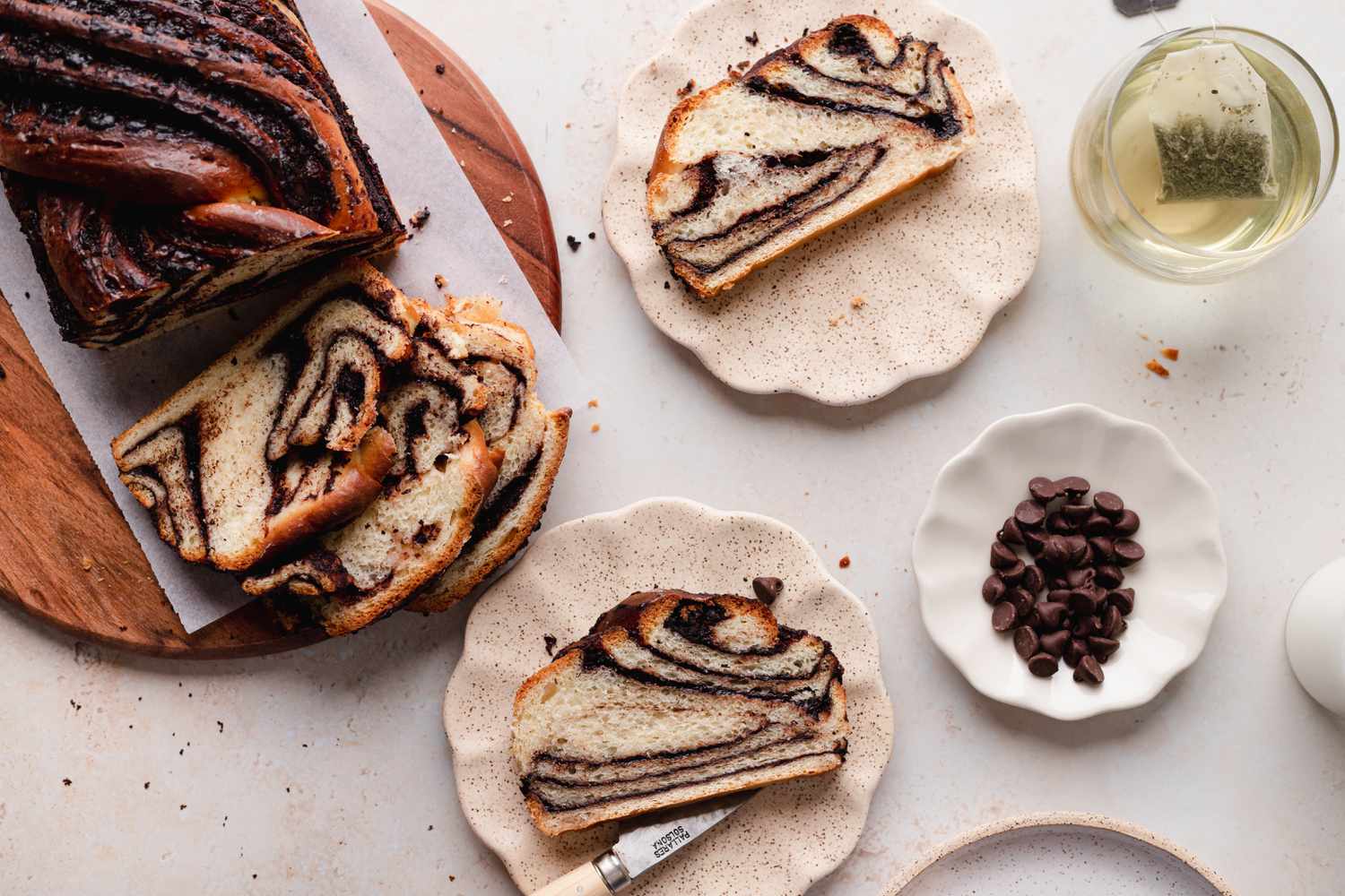 Braided chocolate babka on ruffled plates and with the loaf to the left.