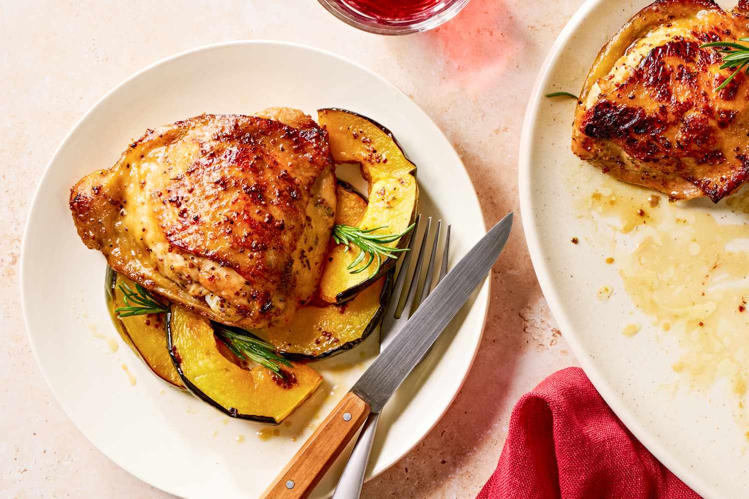 Overhead view of a white plate of a serving of maple glazed chicken and squash with a fork and knife