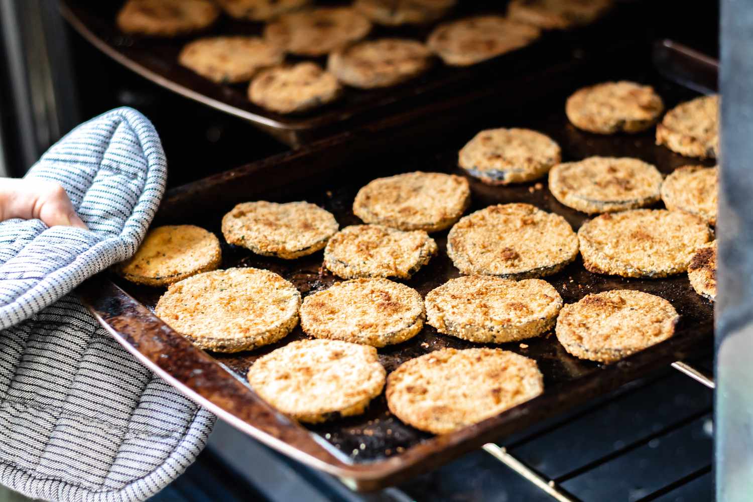 Removing baking sheets with egg plant from an oven
