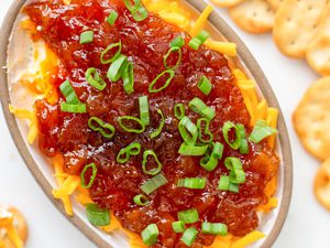 Platter of cheese chutney appetizer with crackers on the counter next to it