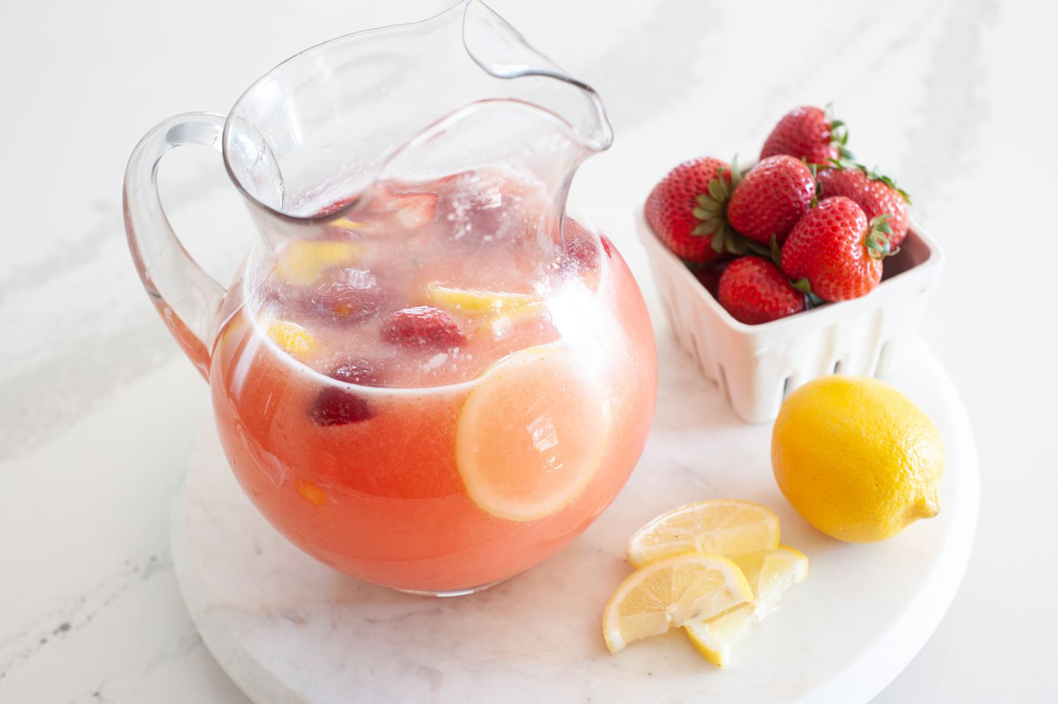 Side view of a pitcher of 100% whole lemon lemonade with strawberry.