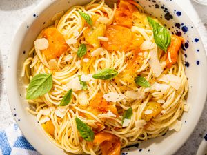 bowl of fresh tomato pasta topped with parmesan shavings and basil leaves (close-up)