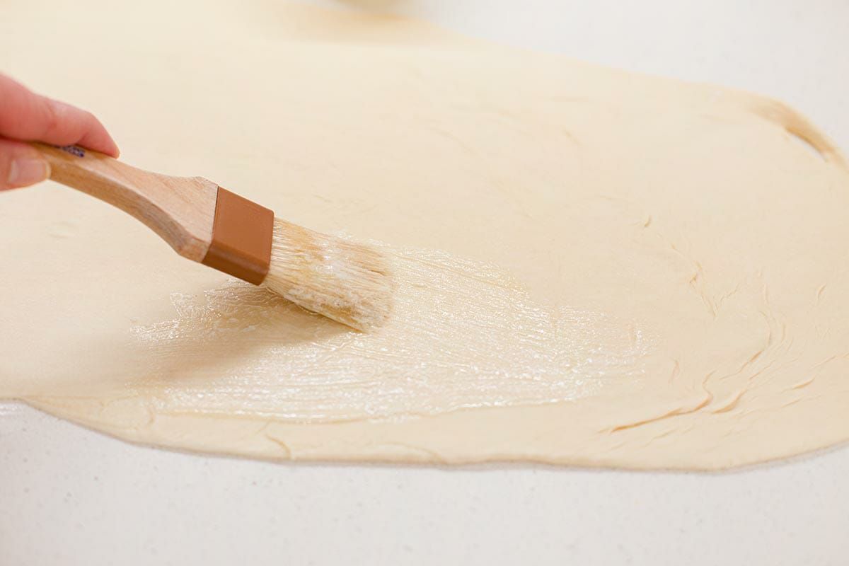 How to make lion house rolls by brushing the rolled out dough with butter.