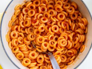 Bowl of ringshaped pasta in tomato sauce with a spoon