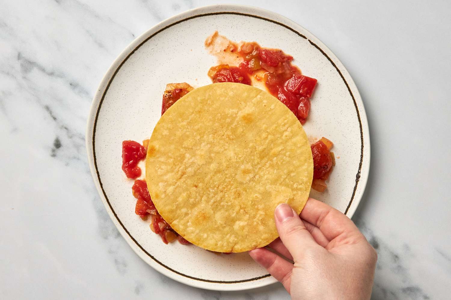 A Toasted Tortilla Added to a Plate Over Some Salsa Smeared for Huevos Rancheros