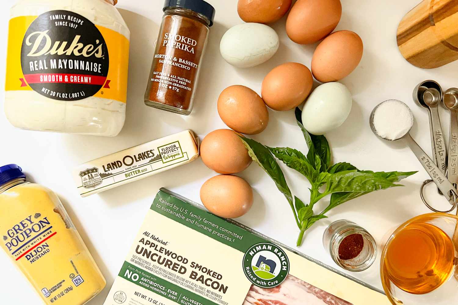 Ingredients laid out for making deviled eggs including eggs mayonnaise bacon smoked paprika and measuring spoons