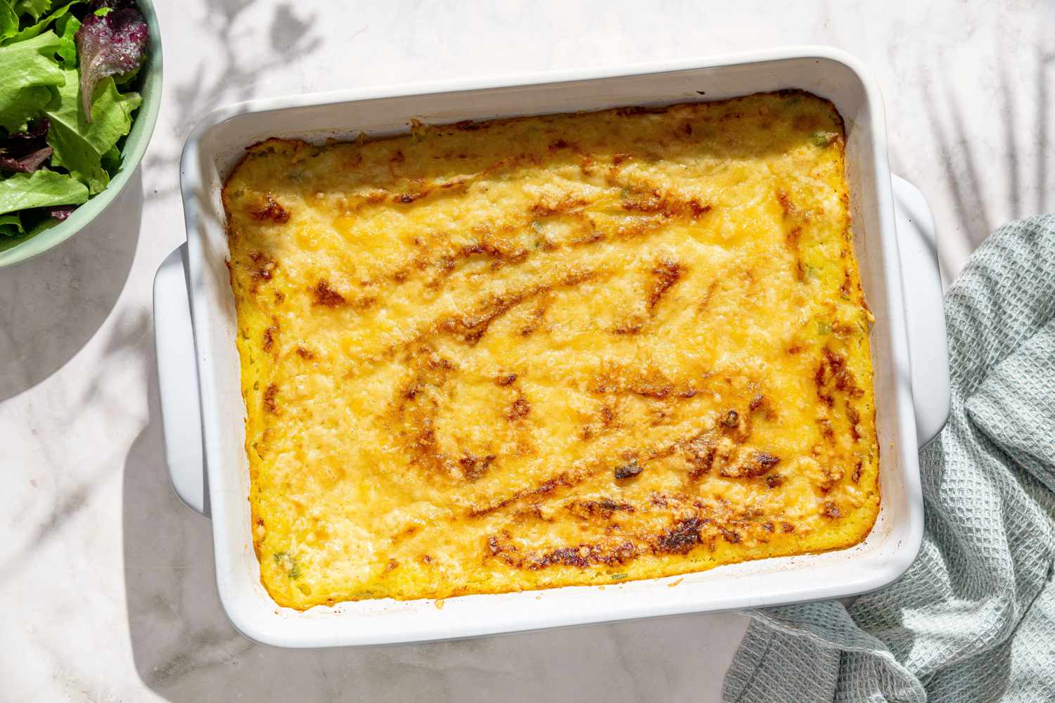 Overheads shot of a white casserole dish with Irish baked mashed potatoes on a white marble counter