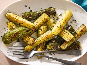 Roasted zucchini served on a white plate with utensils