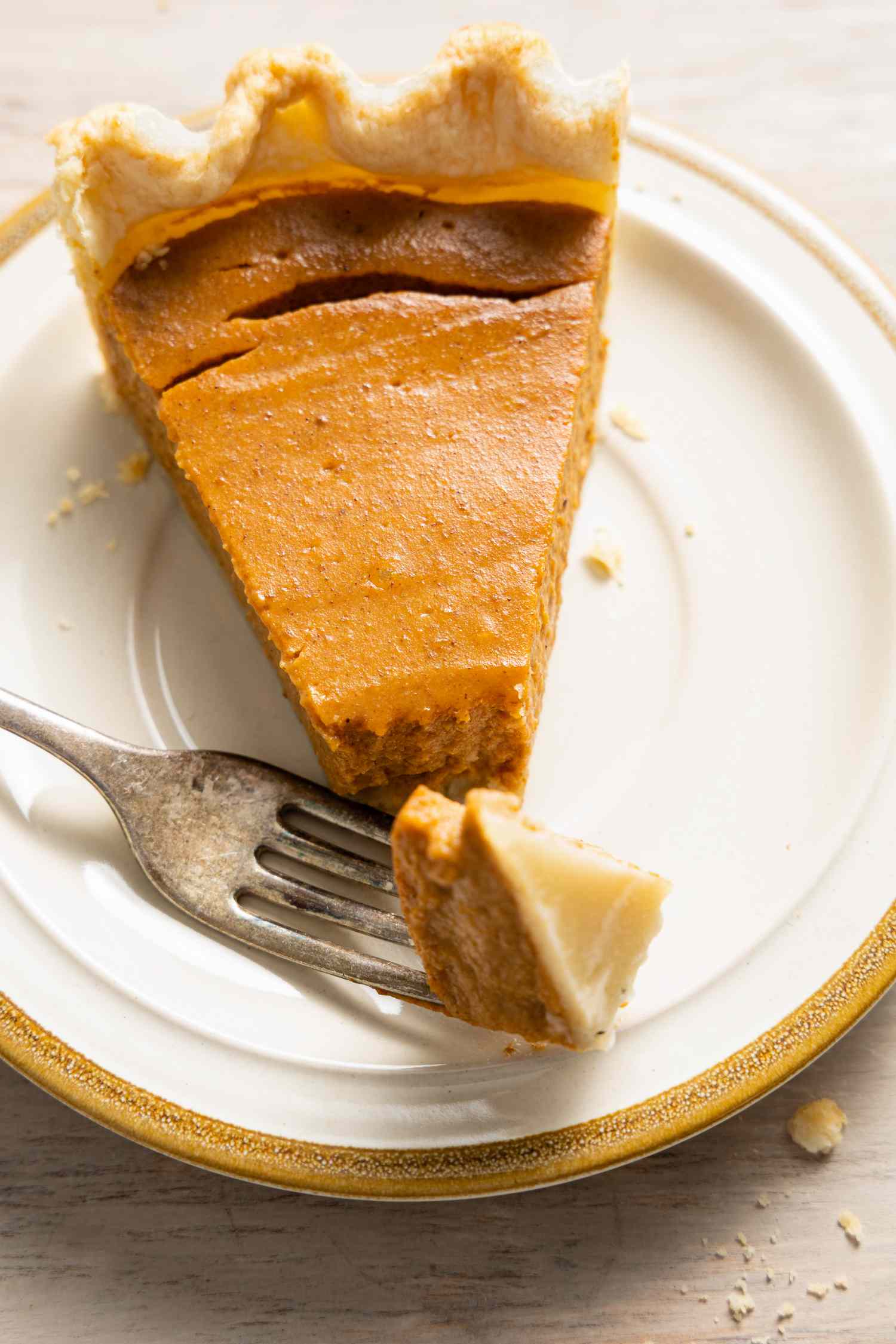 Slice of Vegan Pumpkin Pie on a Small Plate with a Piece Broken Off Using a Fork