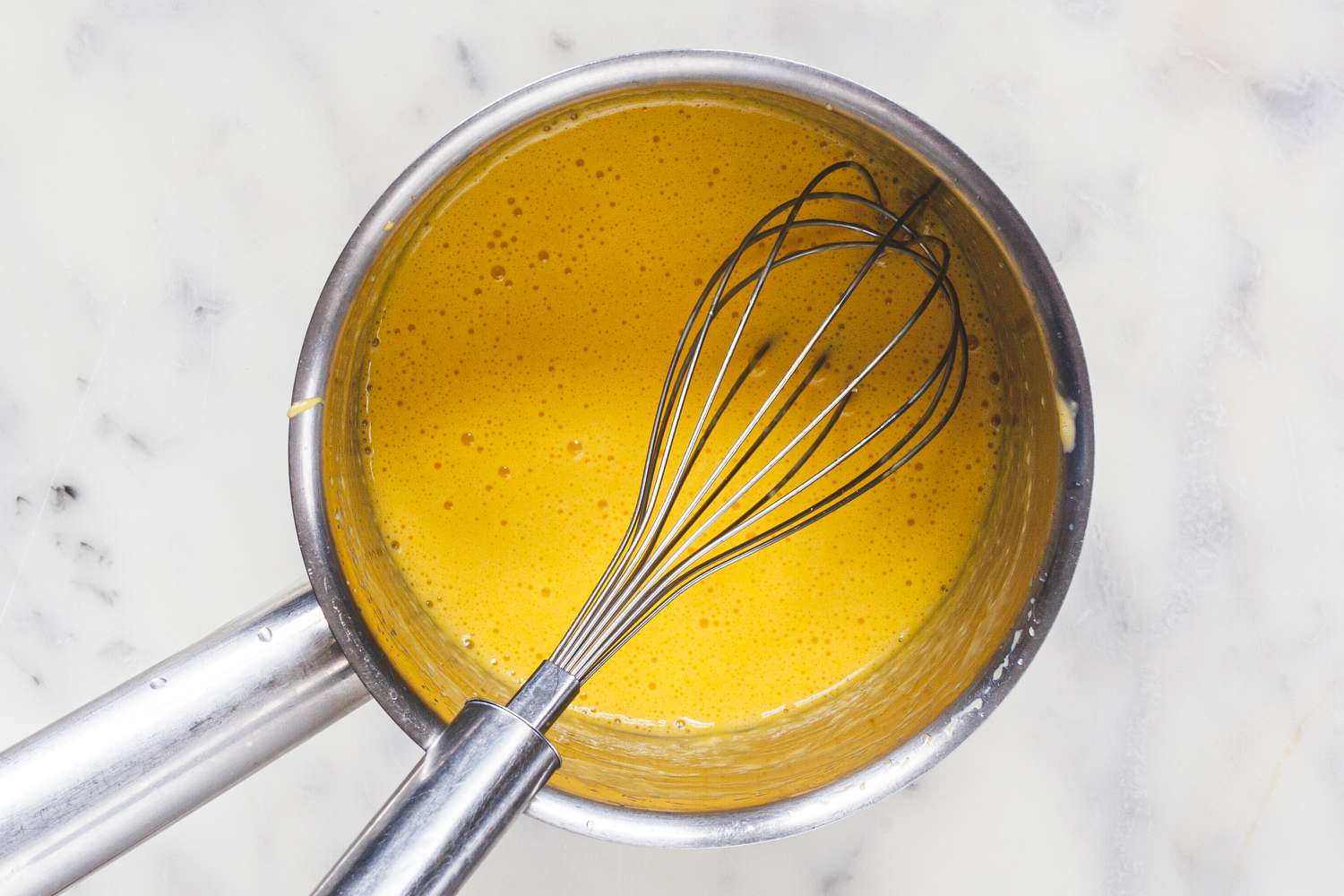 Stovetop Hollandaise Sauce in a pan with a whisk.