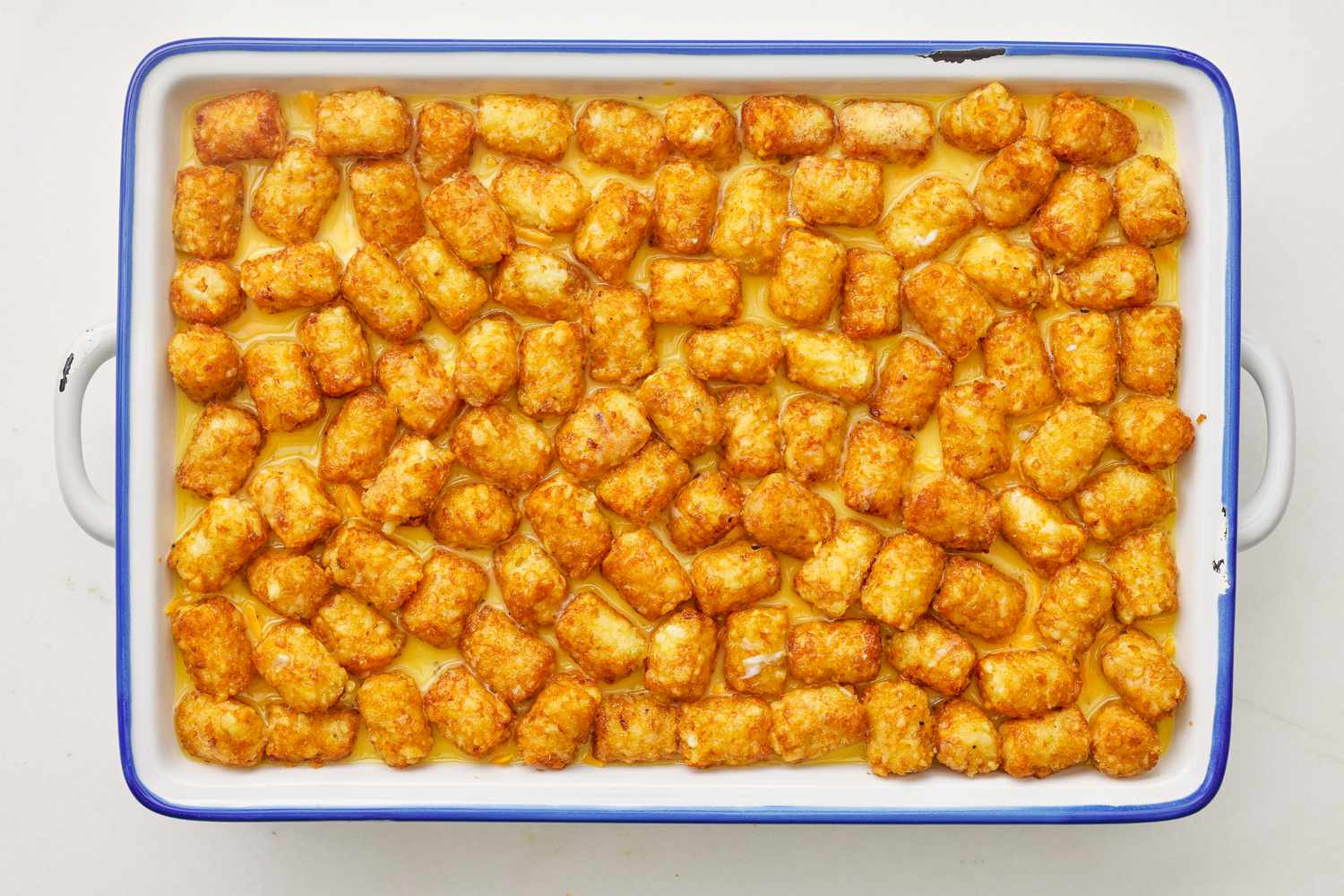 Eggs mixture added to casserole dish on top of the other layers for corned beef tater tot casserole recipe