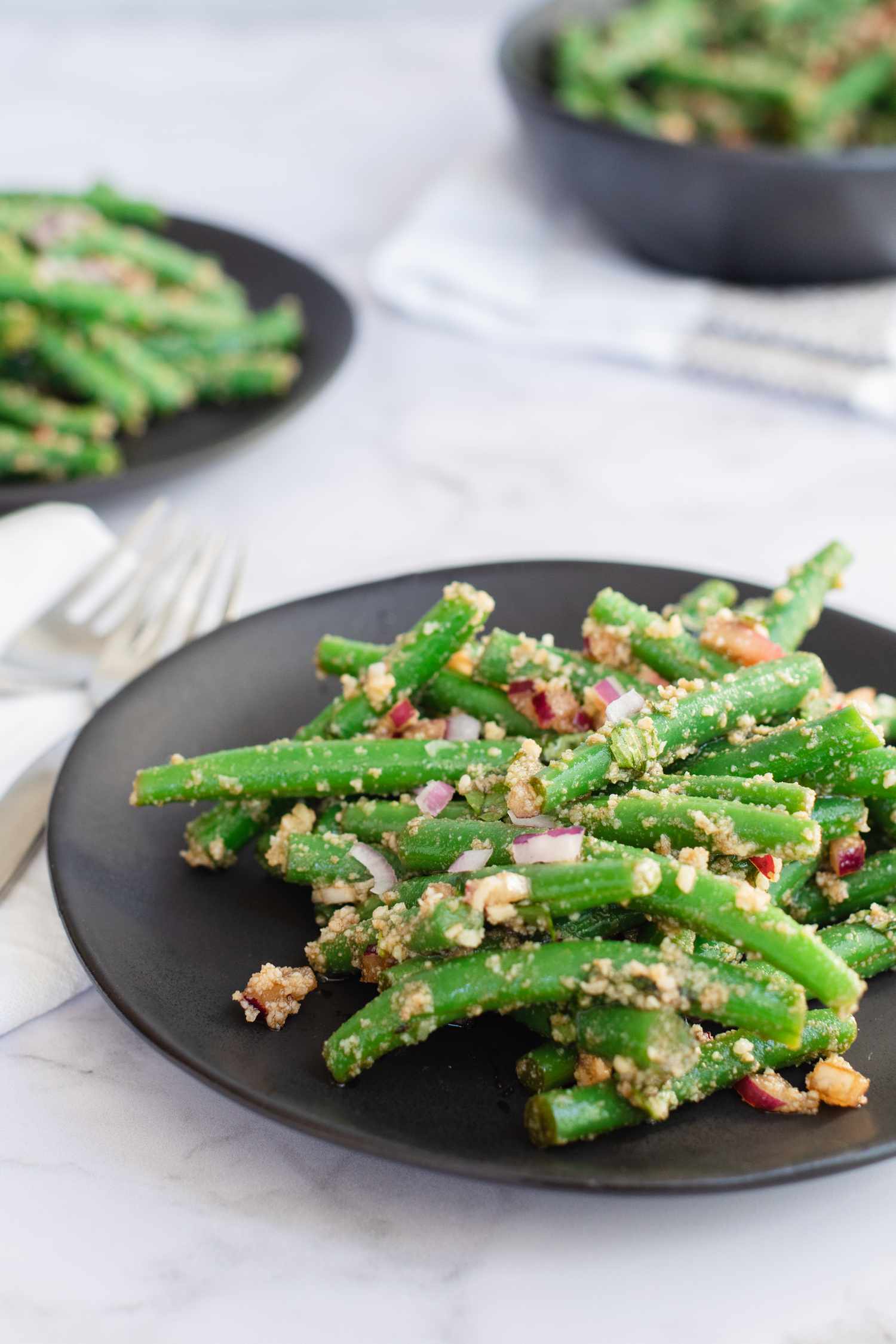 Side view of three plates of green bean salad.