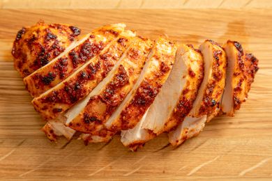 A juicy, spice-encrusted boneless skinless chicken breast sliced on a cutting board