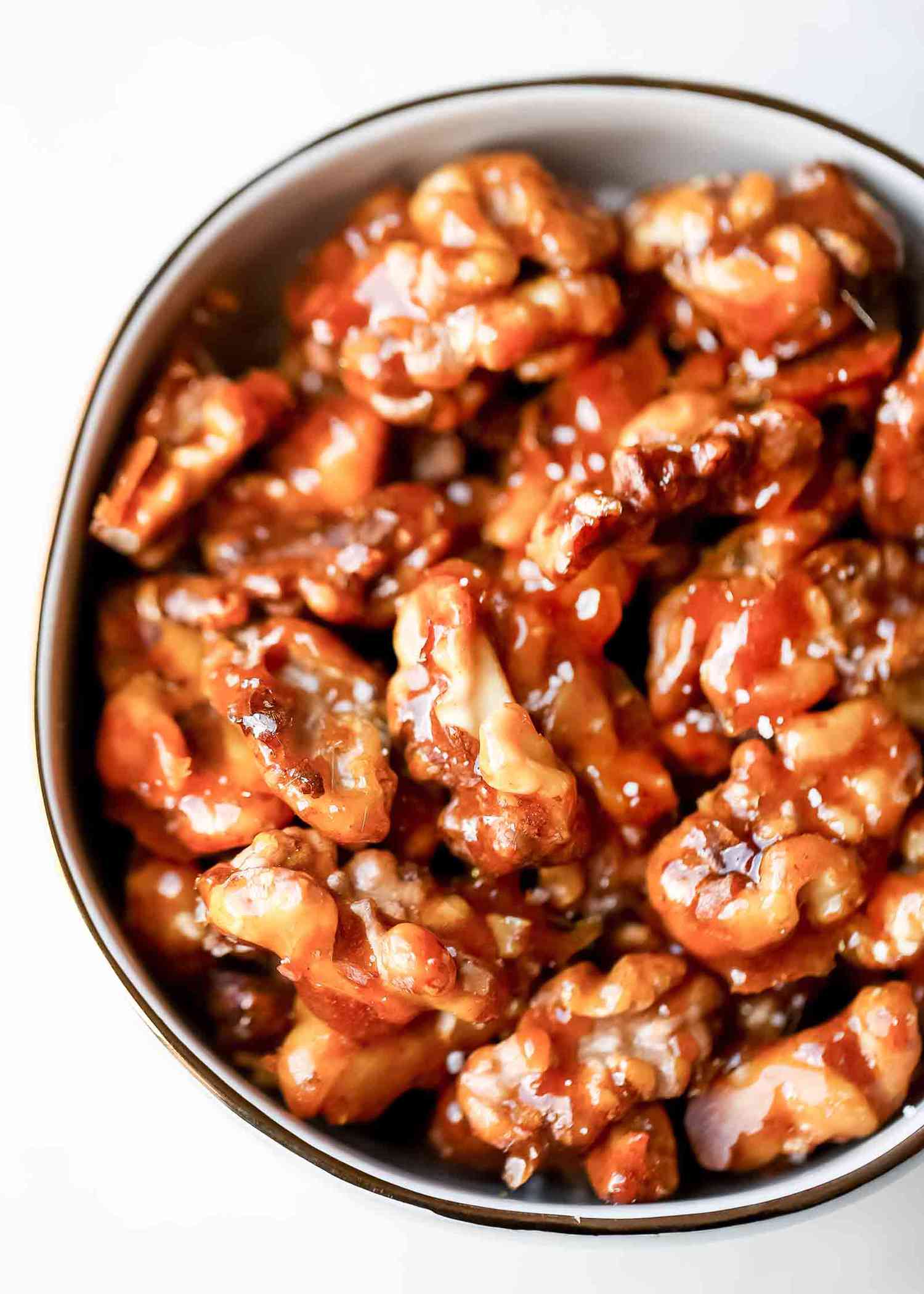 Overhead of candied walnuts in a white bowl