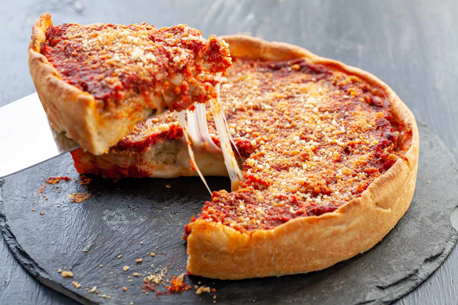 A slice being lifted up from an Italian Sausage Deep Dish Pizza.