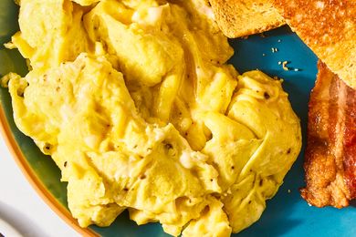 Plate with scrambled eggs toast and a piece of bacon