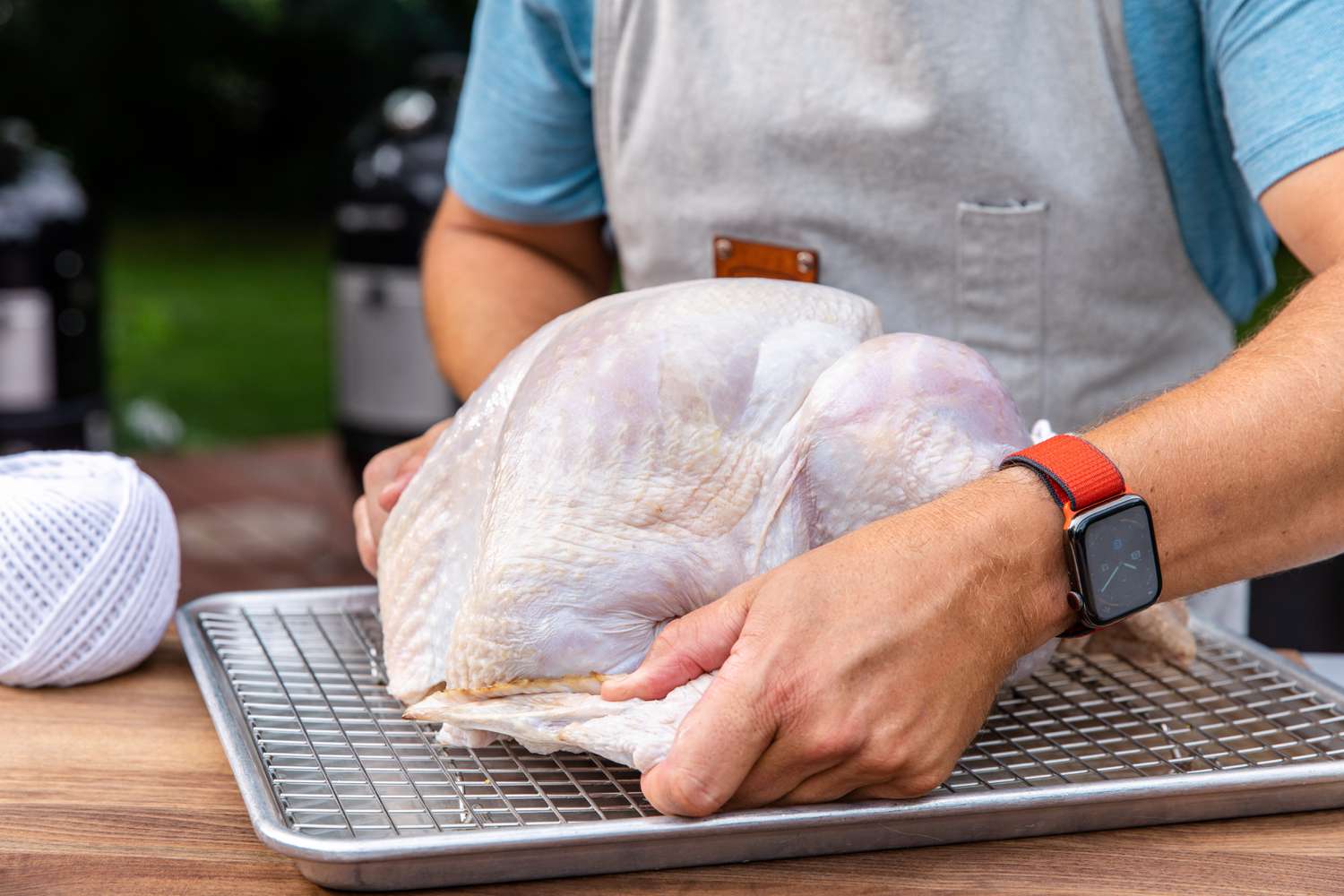 Tucking the wings of a raw turkey to make a smoked turkey.