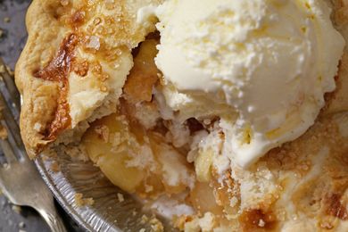 Slice of apple pie topped with a scoop of vanilla ice cream