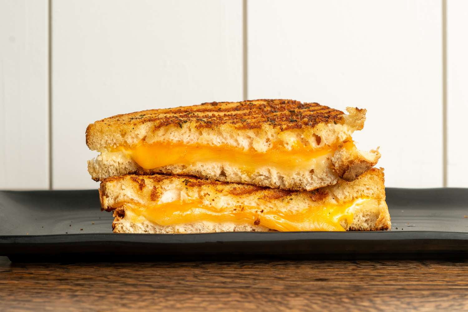 Two halves of a grilled cheese sandwich stacked on a plate