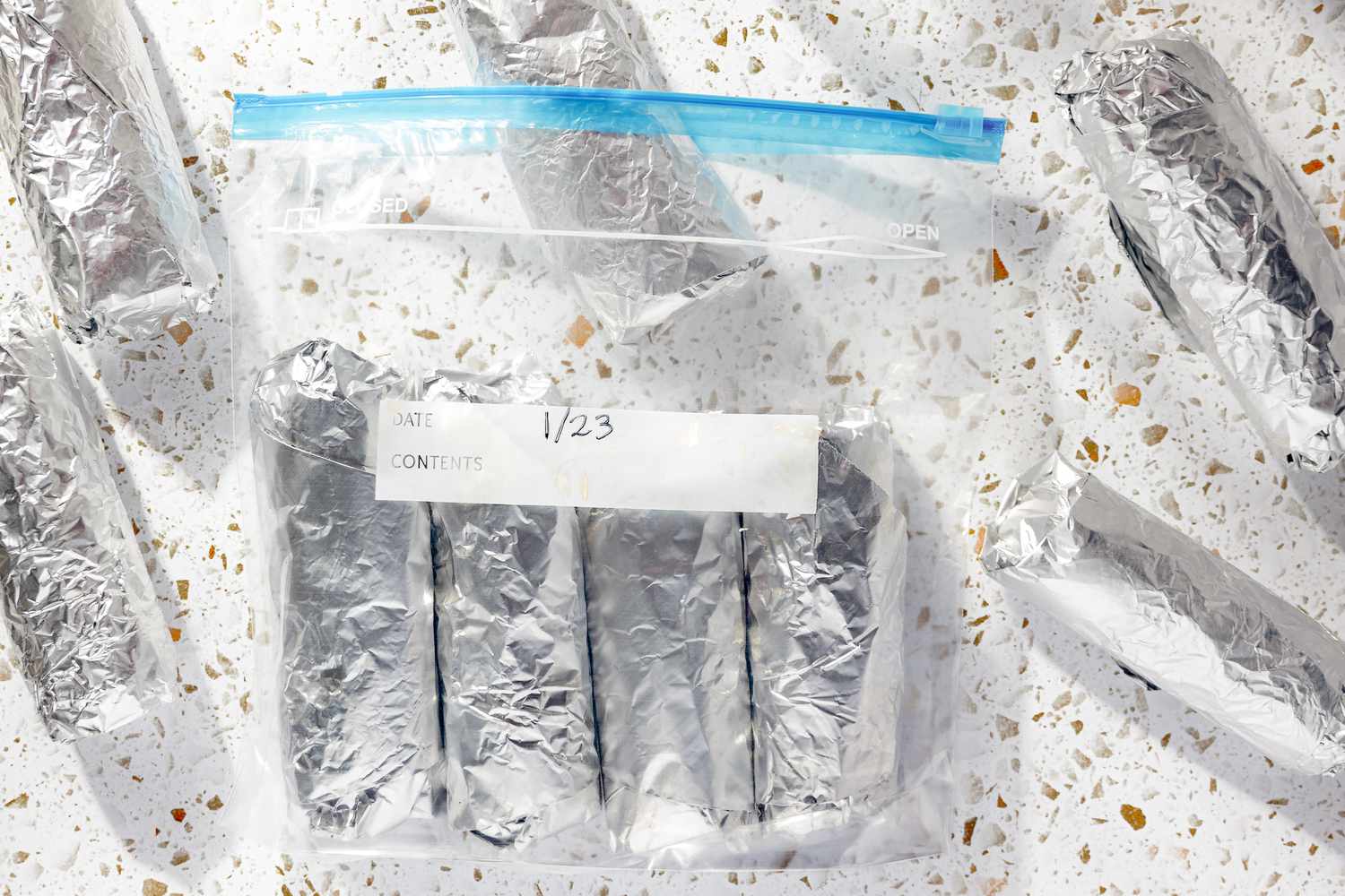 Easy Rice and Beans Freezer Burritos Wrapped in Aluminum Foil (Some on the Counter and Some in a Ziploc Bag)