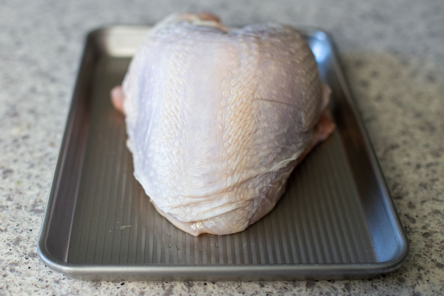 A raw turkey breast on a baking sheet to make Instant pot turkey and gravy.
