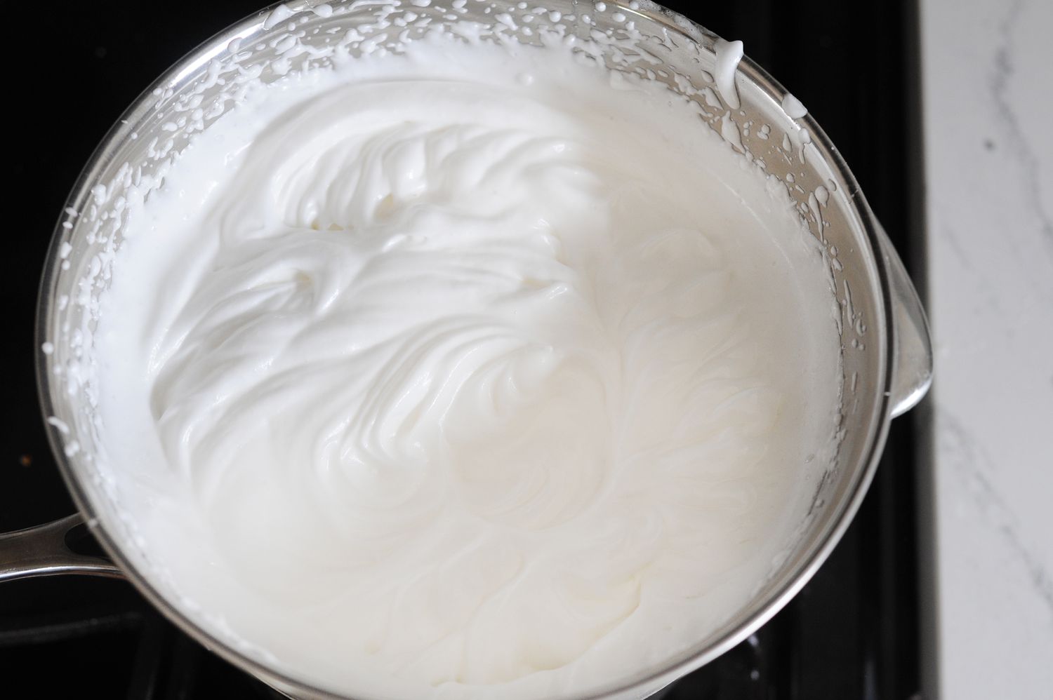 Making the Easiest Frosting Recipe You’ll Ever Make in a metal bowl on the stove.