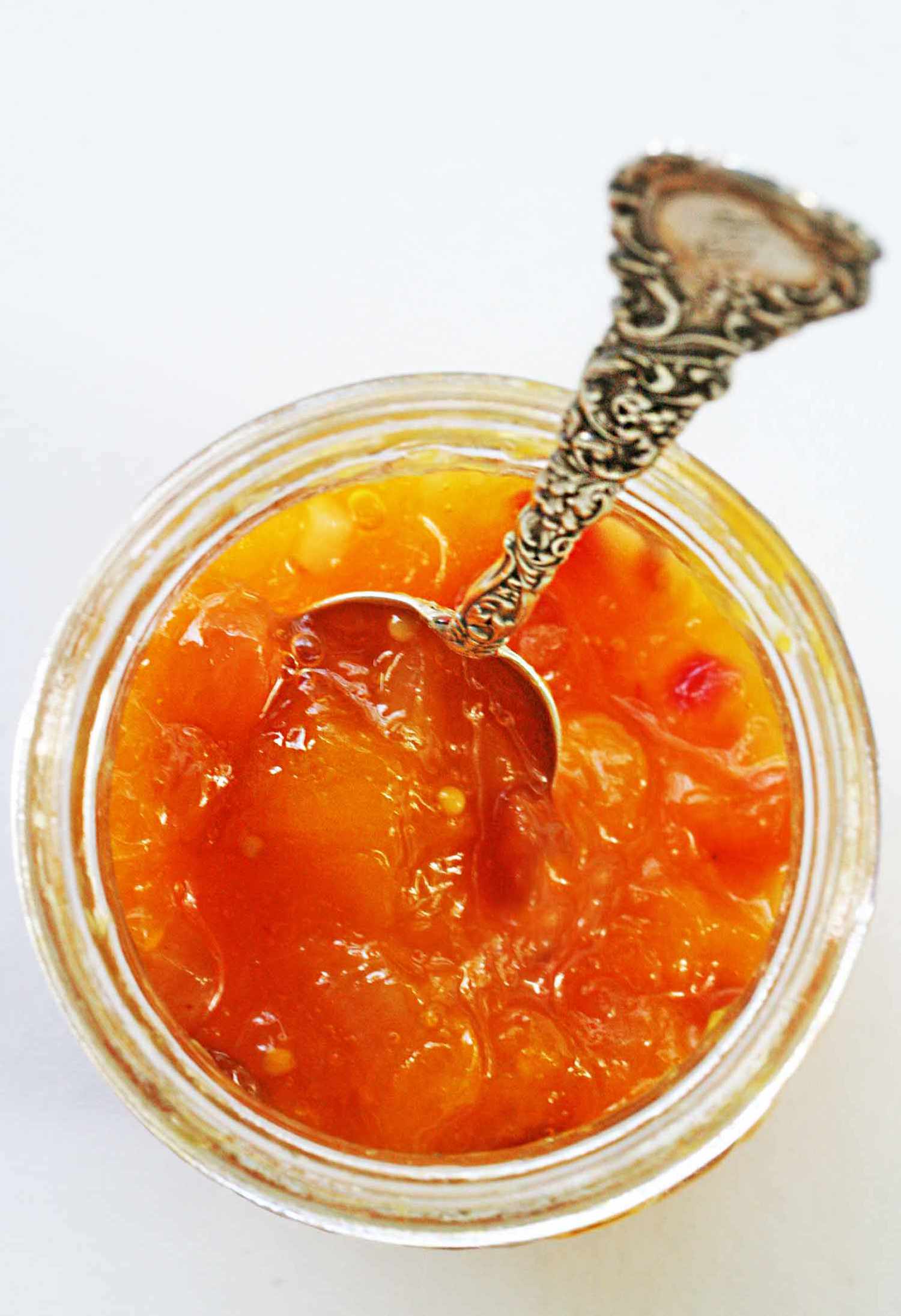 Mango chutney in a jar with a spoon for serving