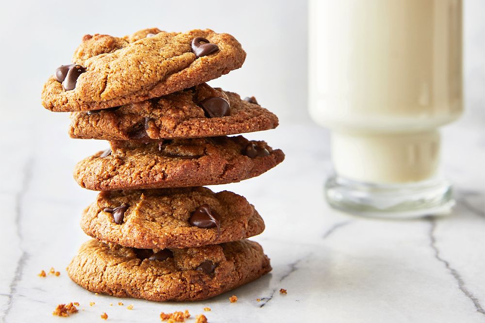 Stack of chocolate chip cookies on a marble surface glass of milk in the background