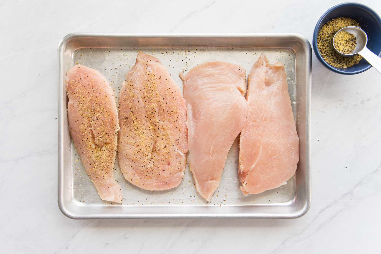 Breast Halves Seasoned with Lemon Pepper on a Baking Tray