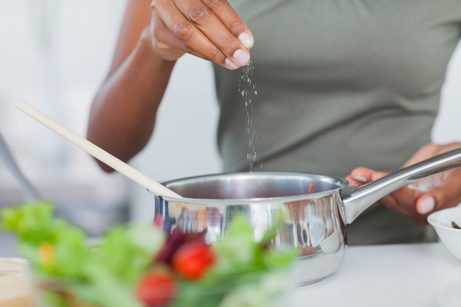 person adding a pinch of salt to pot