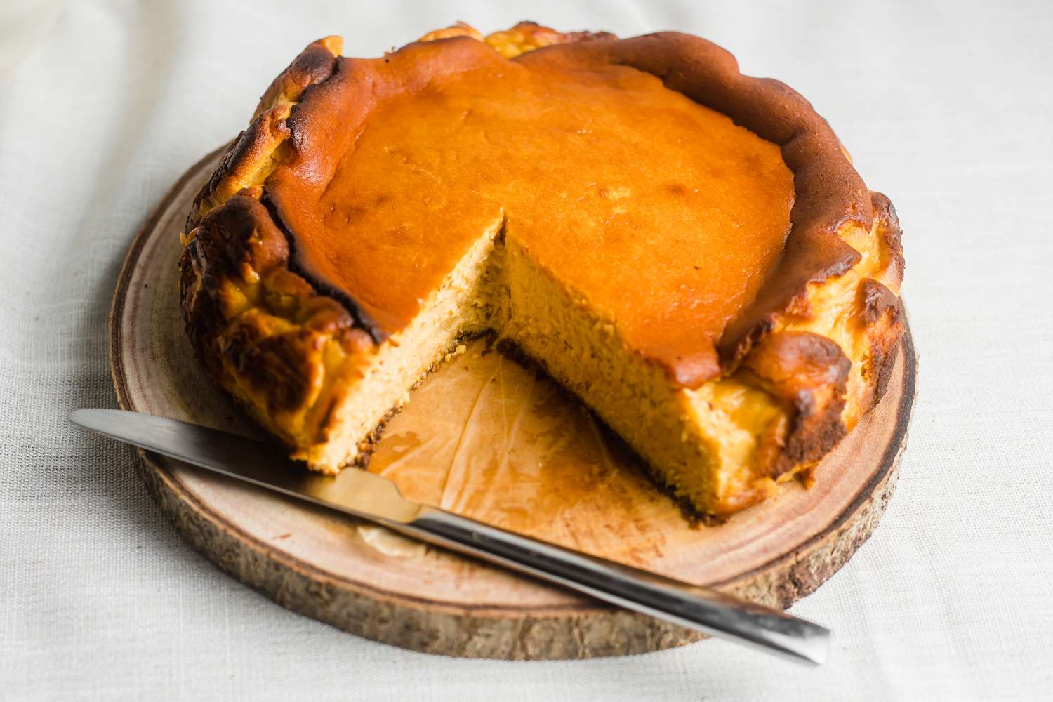 Basque-style cheesecake with slices cut out of it.