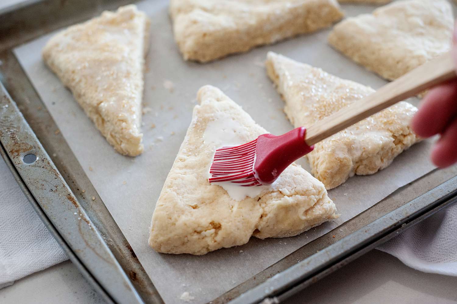Brushing heavy cream on unbaked scones.