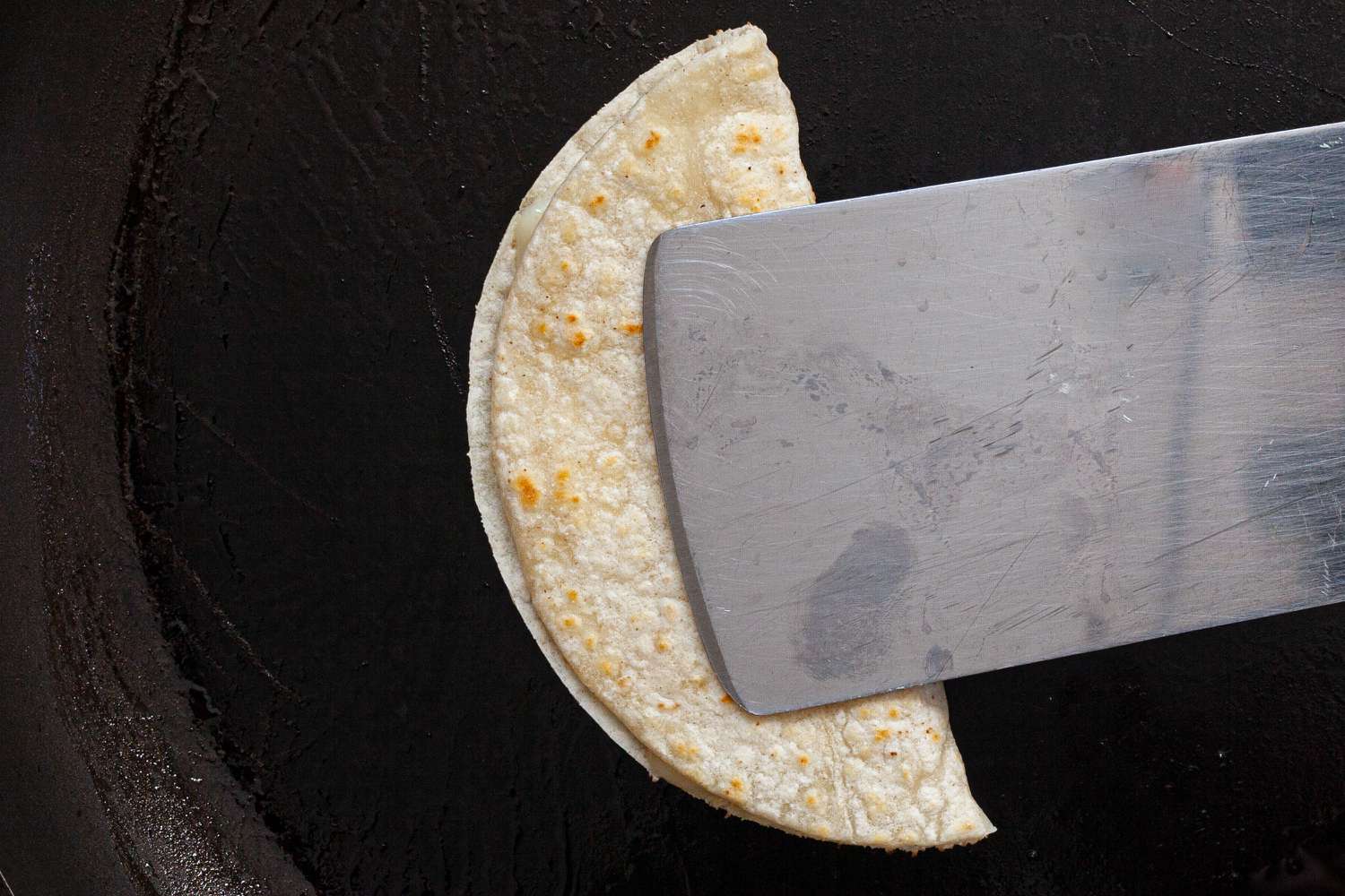 A tortilla pressed in half on a skillet to make a vegetarian tacos recipe.