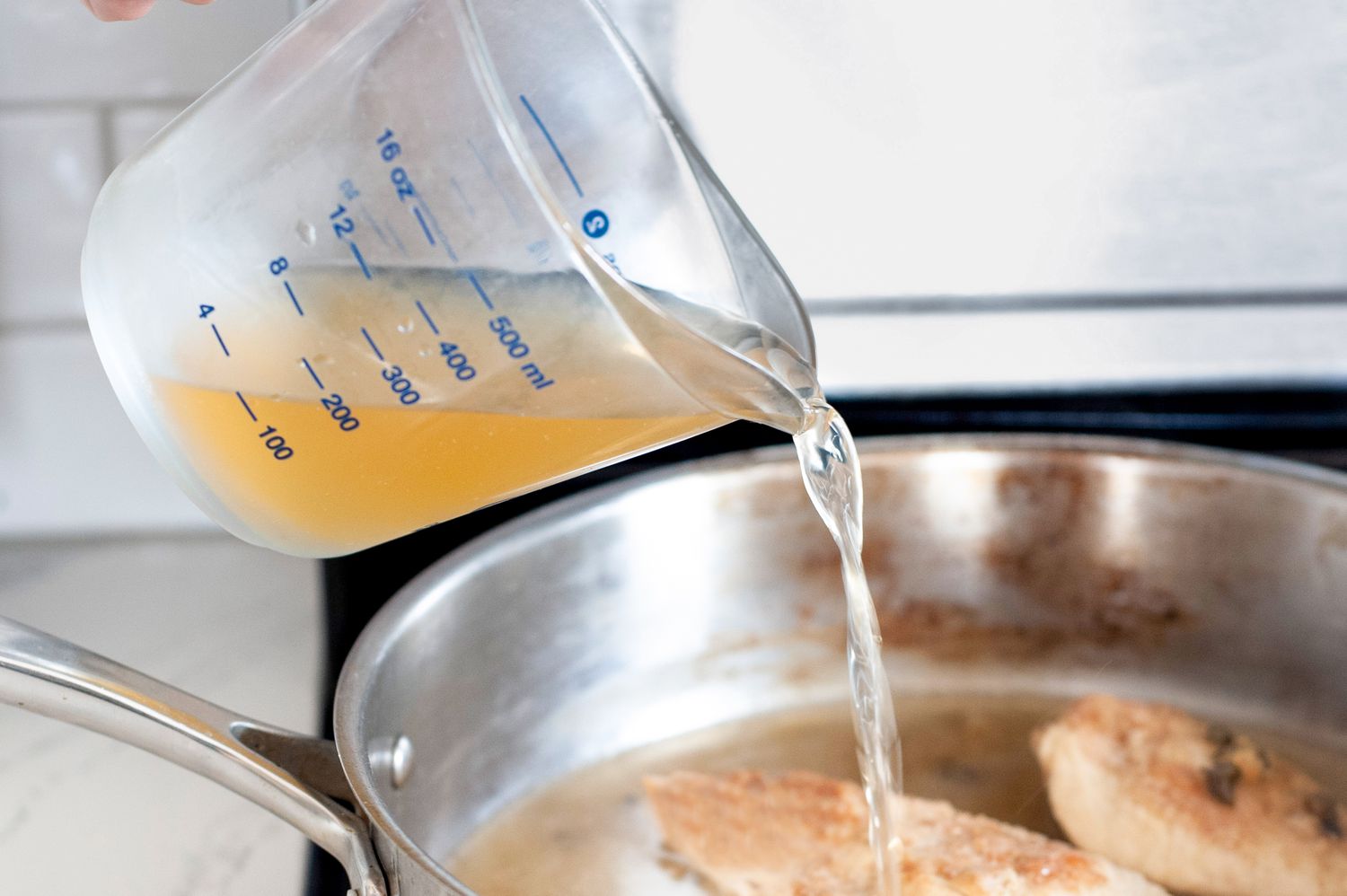 Stock Poured from the Measuring Cup into a Pan on the Stove 