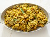 A serving dish filled with stuffing garnished with sage leaves