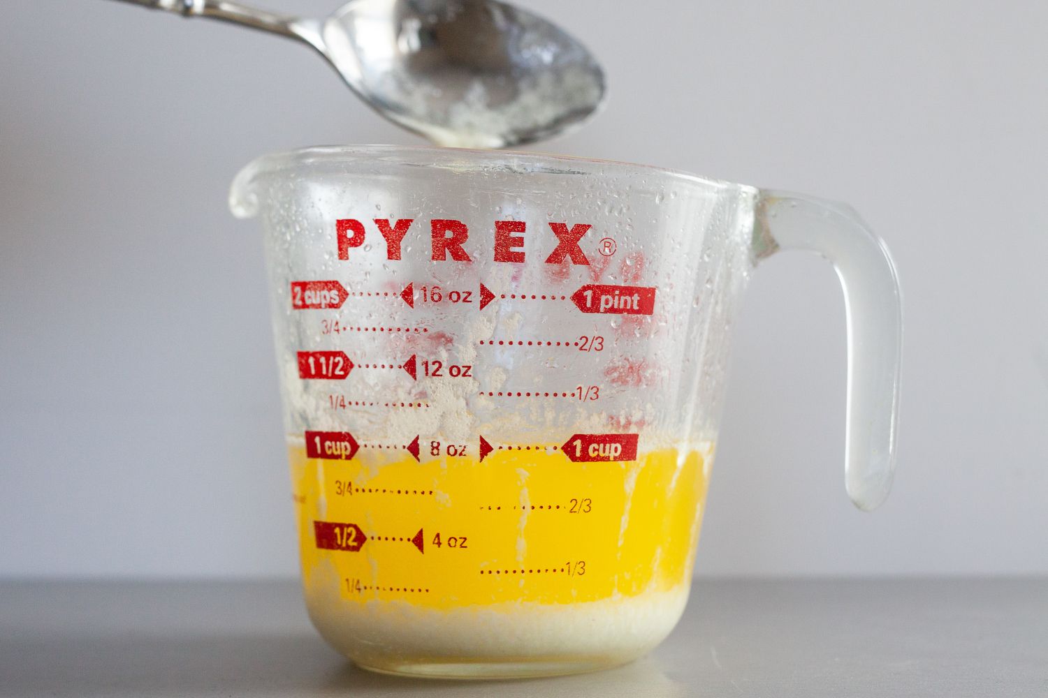 Skimming foam off the top of a measuring cup to make béarnaise sauce.