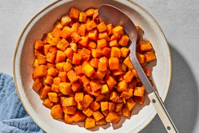 Small cubes of roasted sweet potato in a serving bow, with a serving spoon