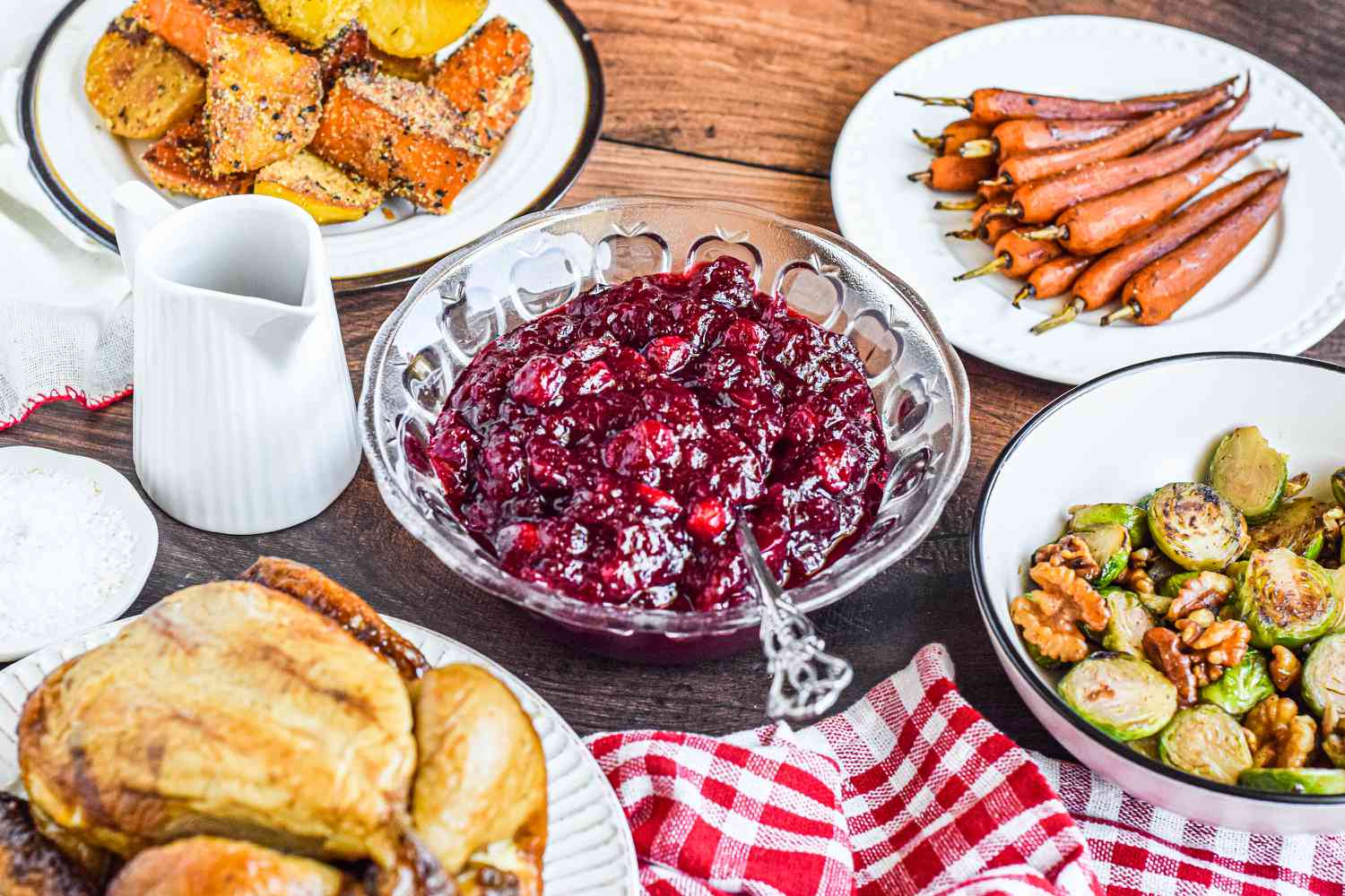 A Thanksgiving table set with a bowl of cranberry sauce next to a platter of turkey and other sides.