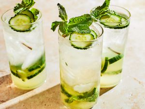 3 cocktail glasses filled with 3-Ingredient Mocktail, garnished with cucumber slices and mint leaves