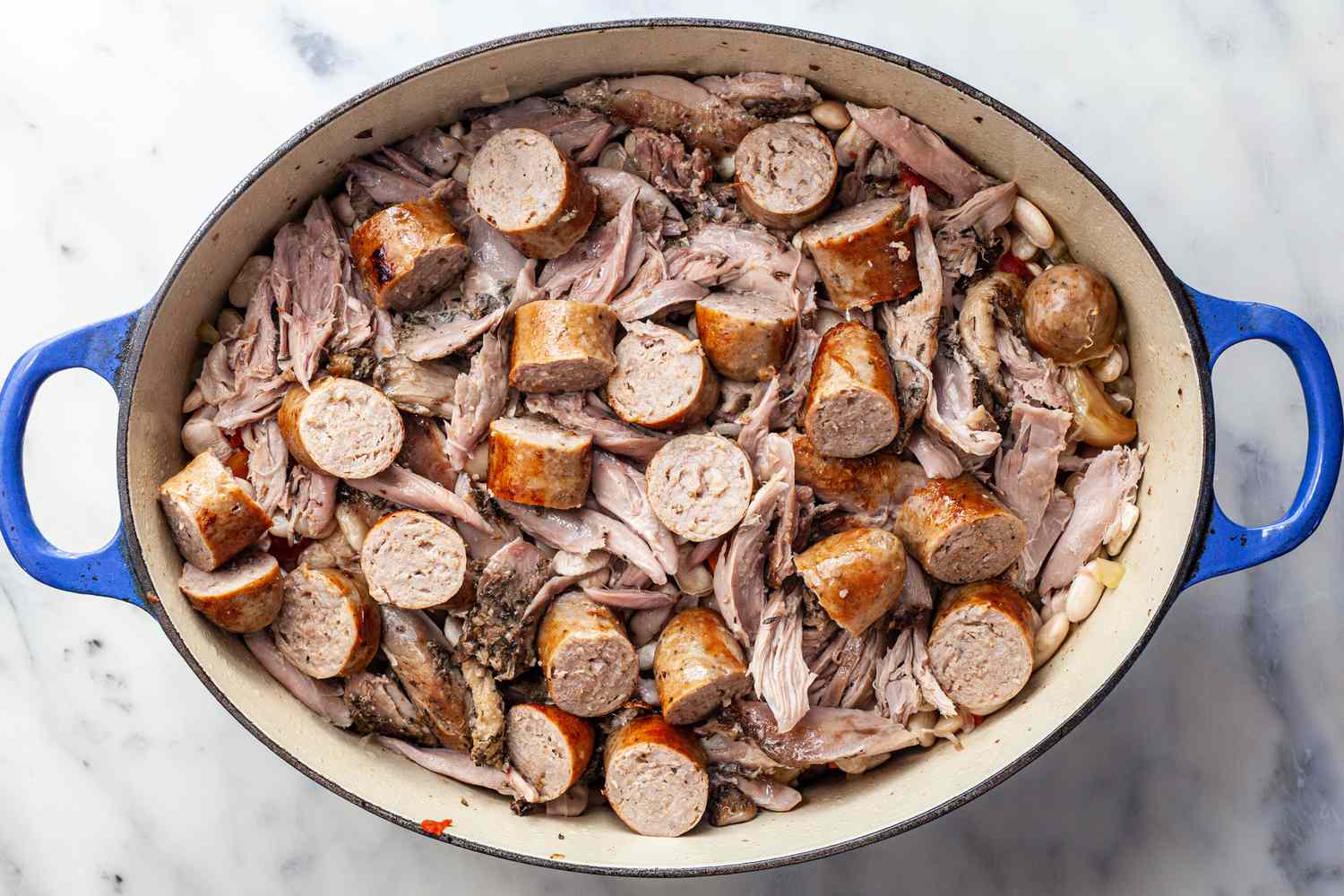 Add duck confit and sausages to Dutch oven.