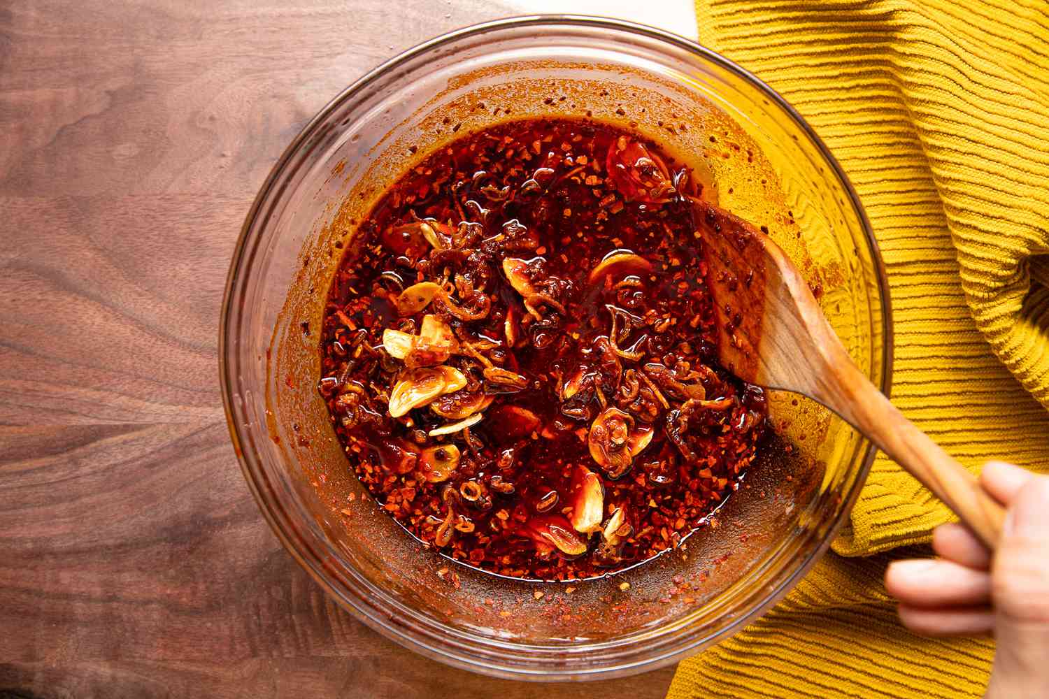 Spatula Mixing Garlic and Shallots Into Bowl With Pepper and Oil Mixture