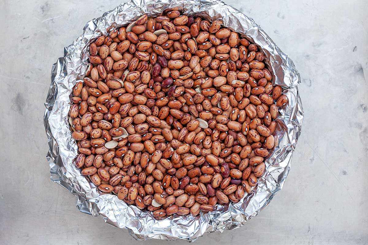 Homemade quich crust is ready for parbaking. It is covered with foil and has dried beans inside.