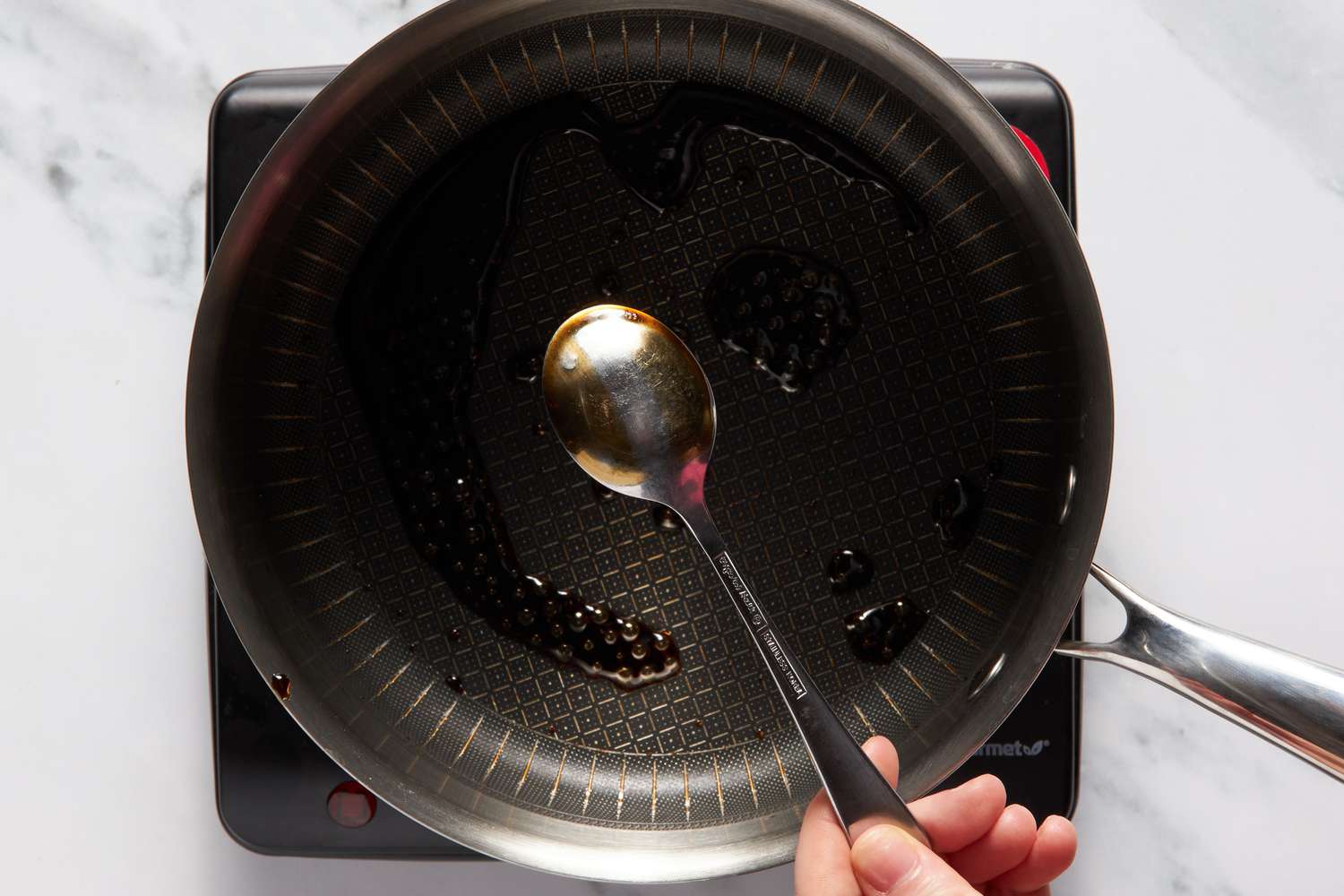 Reduced Dr. Pepper on a spoon to showcase desired texture for Dr. Pepper cake recipe