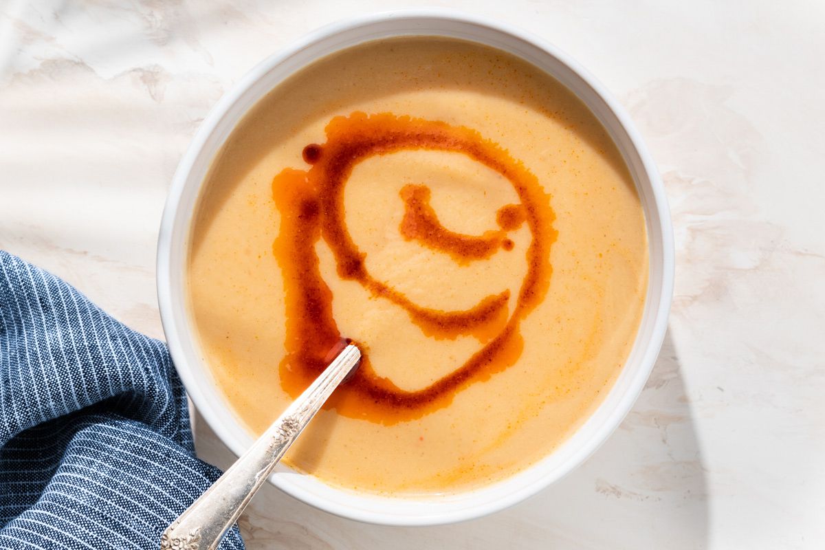 Overhead view of 4-ingredient cauliflower soup drizzled with paprika oil in a white bowl